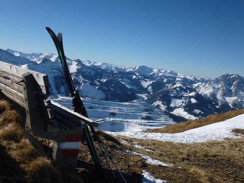 Angelehnte Skier an einer Holzbank mit Blick auf das umliegende Bergpanorama